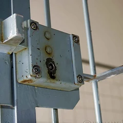 A metal lock box with a keyhole on a gate