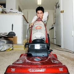 A person pushing a red upright vacuum cleaner